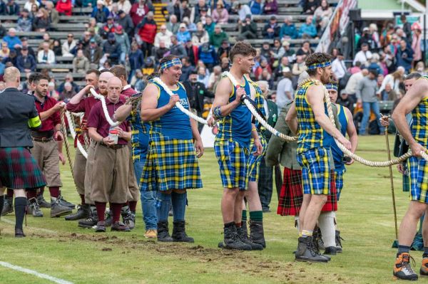 Participants in tartan attire prepare for a tug-of-war at a sports event.